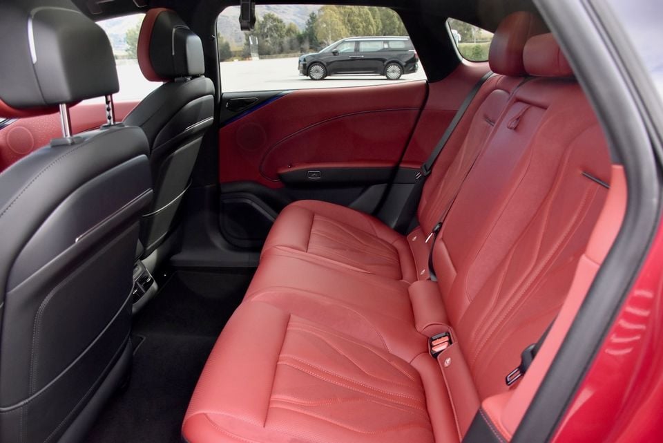 Red leather rear seats inside a Zeekr 7GT, viewed through the open rear door with black trim accents and a sloping roofline visible