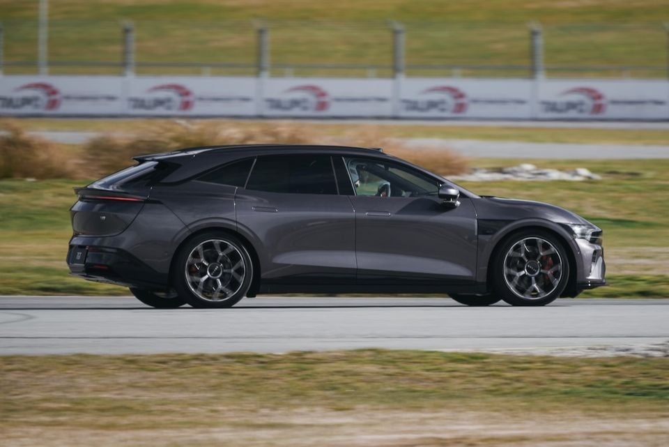A dark grey Zeekr 7GT wagon driving on a race track, seen from the side