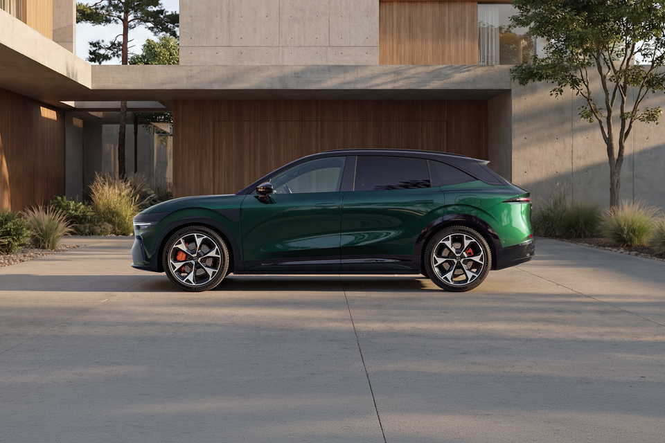 Um SUV elétrico verde 2027 Zeekr 7X estacionado lateralmente na entrada de uma moderna casa de concreto e madeira
