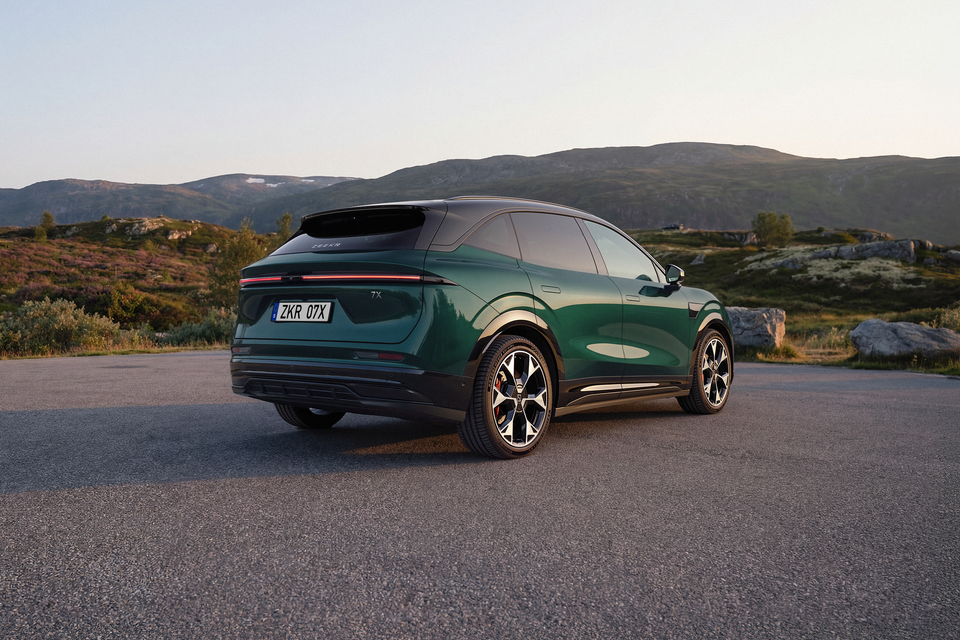 A green 2027 Zeekr 7X electric SUV parked on a mountain road, seen from the rear passenger side at sunset