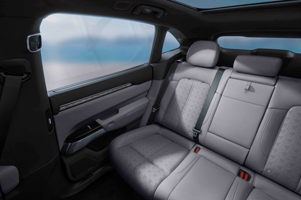 Rear seats of the 2027 Zeekr 7X with light grey perforated upholstery, seen through the open rear door, with a panoramic glass roof above