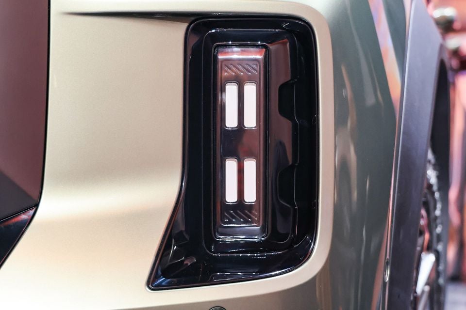 Close-up of the LED light cluster set into the satin gold bumper of a 2027 Chery Tiggo X7, beside the wheel arch