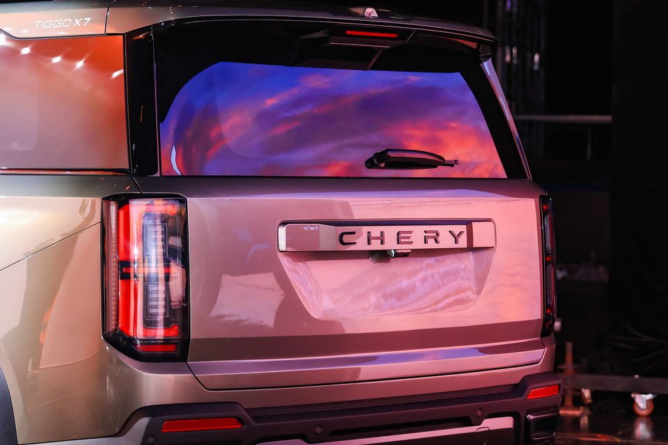 Rear of a 2027 Chery Tiggo X7 SUV showing its tailgate, Chery lettering and tail-lights under coloured stage lighting