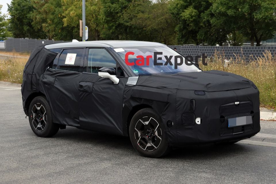 A camouflaged Kia Sportage SUV prototype seen from the front-side during road testing