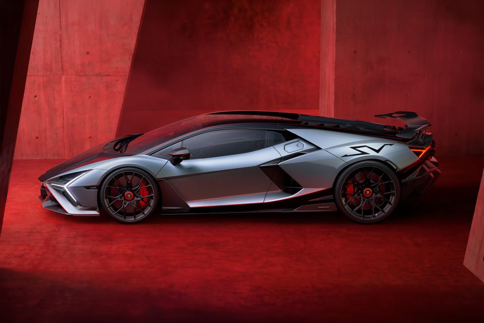 A silver Lamborghini Revuelto SV supercar photographed from the side in a dramatic red-lit studio setting, showing its aggressive aerodynamic bodywork and large rear wing