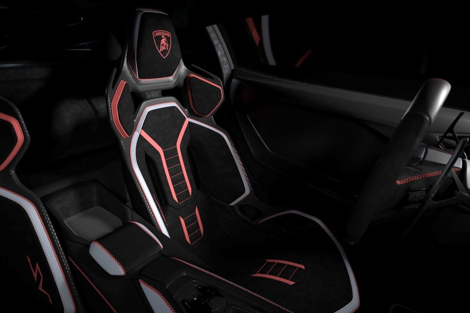 Lamborghini Revuelto SV interior showing sculpted bucket seats in black alcantara with red and silver contrast stitching and carbon fibre trim, with the Lamborghini logo embroidered on the headrest