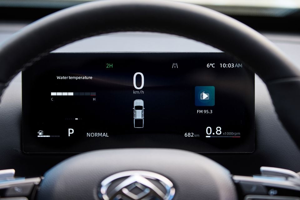 The digital instrument cluster of a 2027 LDV T60 Luxe shows speed, water temperature and drive mode information, viewed through the steering wheel.