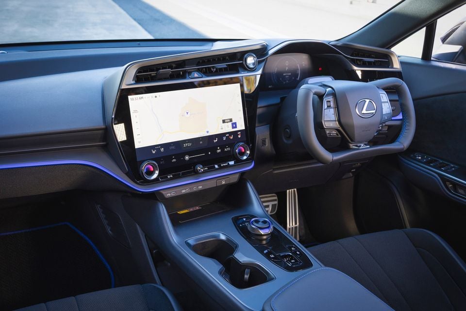 The interior of a Lexus RZ600e electric SUV, showing the yoke-style steering wheel, digital instrument cluster and central touchscreen with navigation map.
