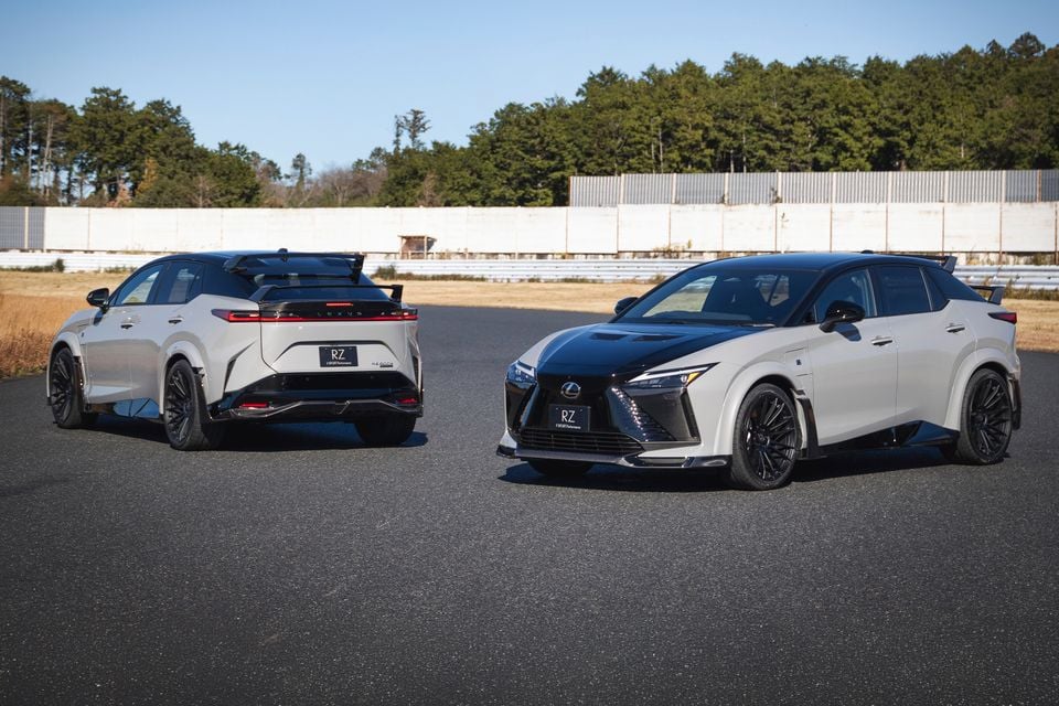 Two white Lexus RZ600e F Sport Performance electric SUVs parked on a track, one shown from the rear and the other from the front quarter.