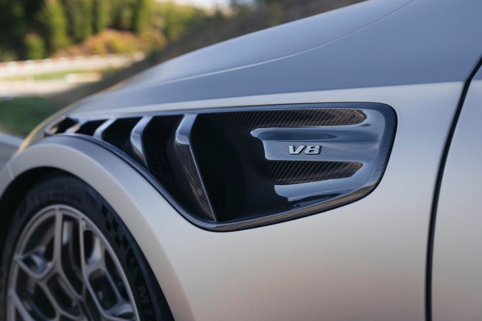 Close-up of the carbon fibre side vent with a V8 badge on a silver Mercedes-AMG CLE