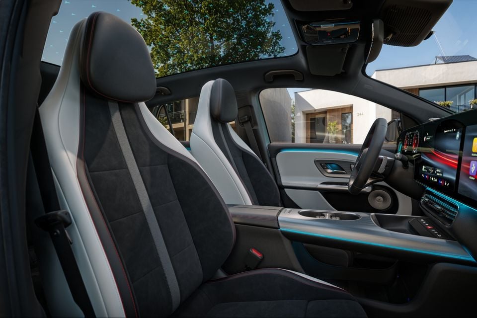 Interior of a 2027 Mercedes-Benz GLA showing front seats with two-tone black and white upholstery, red stitching, ambient lighting, panoramic sunroof, and infotainment screen on the dashboard