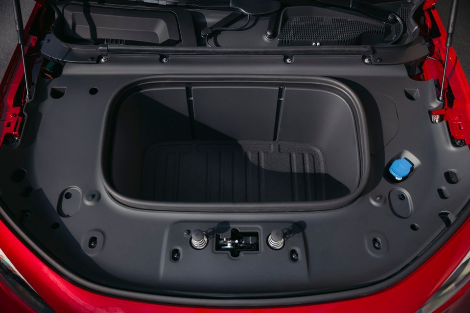 The front trunk (frunk) storage compartment of a red Mercedes-Benz GLA, viewed from above with the bonnet open, showing an empty storage well.