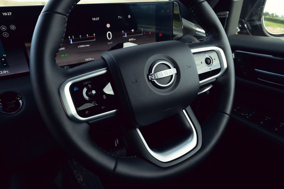 Nissan Patrol Y63 interior showing the leather-wrapped steering wheel with Nissan logo, digital instrument cluster, and infotainment screen