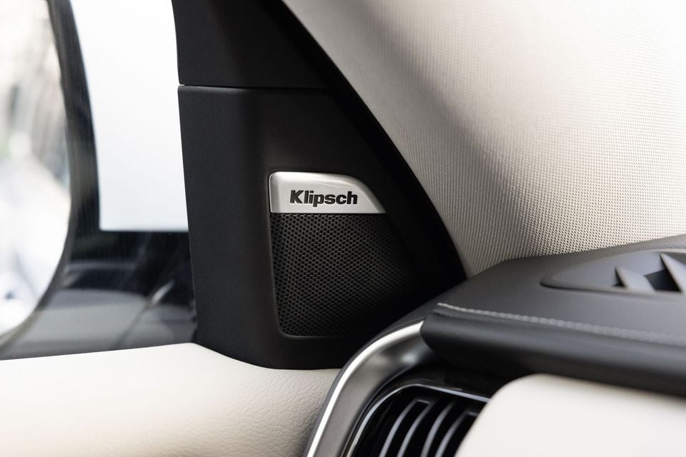 A Klipsch speaker mounted on the A-pillar interior trim of a Nissan Patrol Y63, with light-coloured cabin upholstery visible nearby.