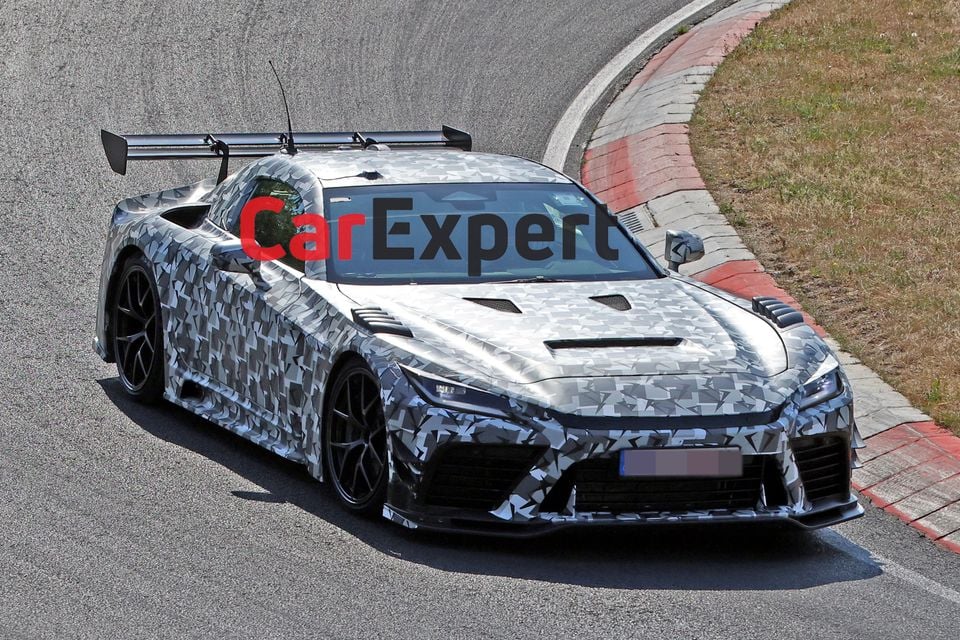 A camouflaged Toyota GR GT3 supercar prototype with a large rear wing on track at the Nurburgring, seen from the front three-quarter angle