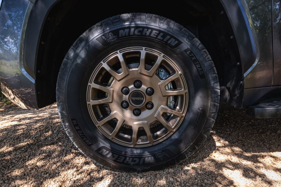 Close-up of a bronze alloy wheel with Michelin LTX Trail tyre on a Toyota Tundra TrailHunter, parked on gravel