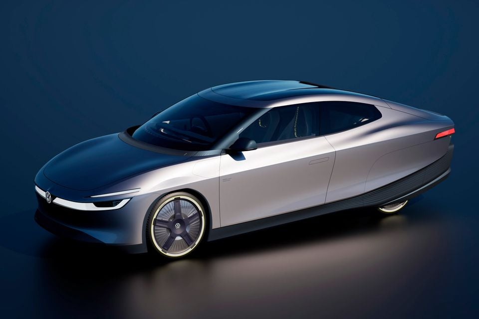 A Volkswagen concept car with a sleek silver and dark two-tone fastback body, seen from a front three-quarter angle in a studio setting