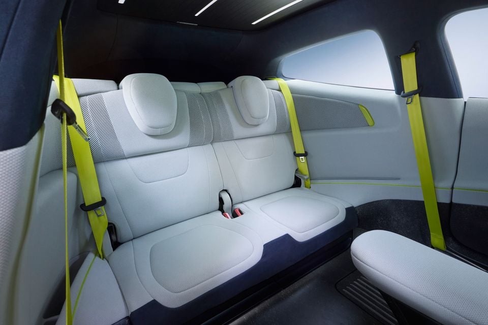 The rear seat interior of a concept car featuring light grey upholstery with bright yellow-green seatbelts