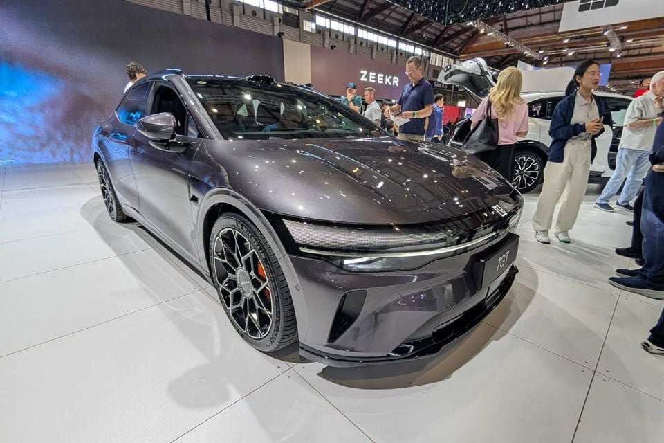 A dark grey Zeekr 7GT sedan on display at a motor show, seen from the front quarter angle