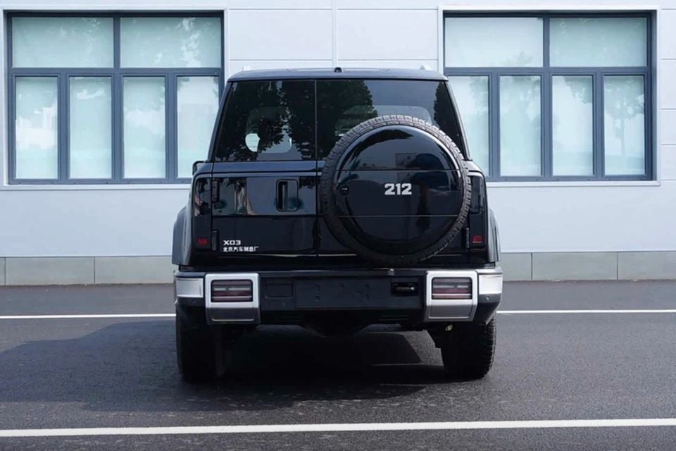 Rear view of a black BAIC 212 X03 SUV with a rear-mounted spare wheel, seen from behind in a car park