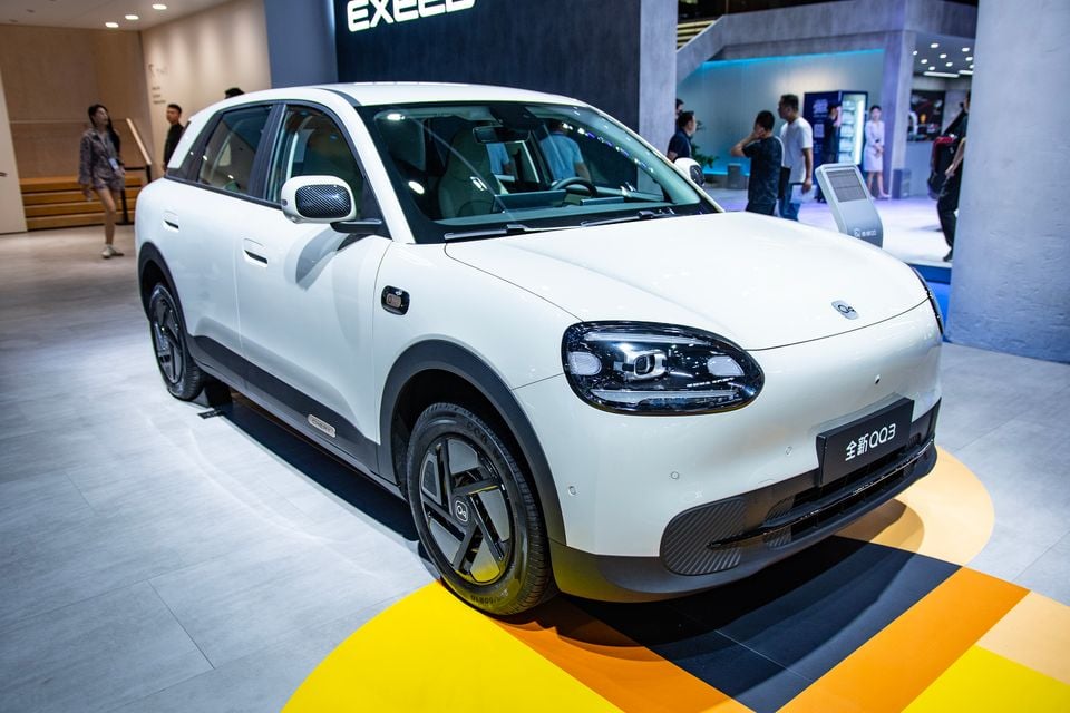 A white Chery QQ3 small SUV on display at a motor show, seen from the front-side angle