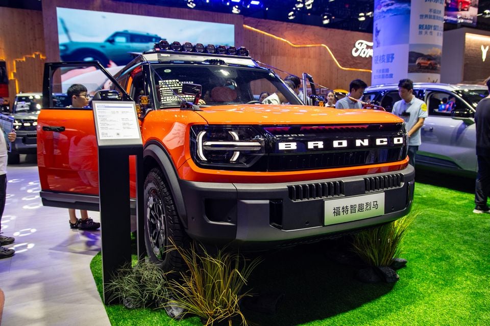 An orange Ford Bronco Sport SUV on display at the Chengdu Motor Show, seen from the front three-quarter angle with a roof-mounted light bar and open door