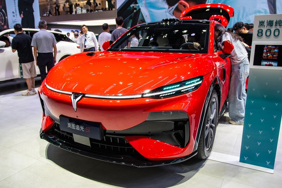 A red Voyah Passion S electric sedan displayed at a motor show, seen from the front