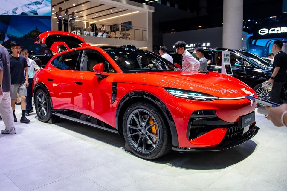 A red Voyah Passion S electric SUV coupe on display at a motor show, seen from the front-side angle with the boot open