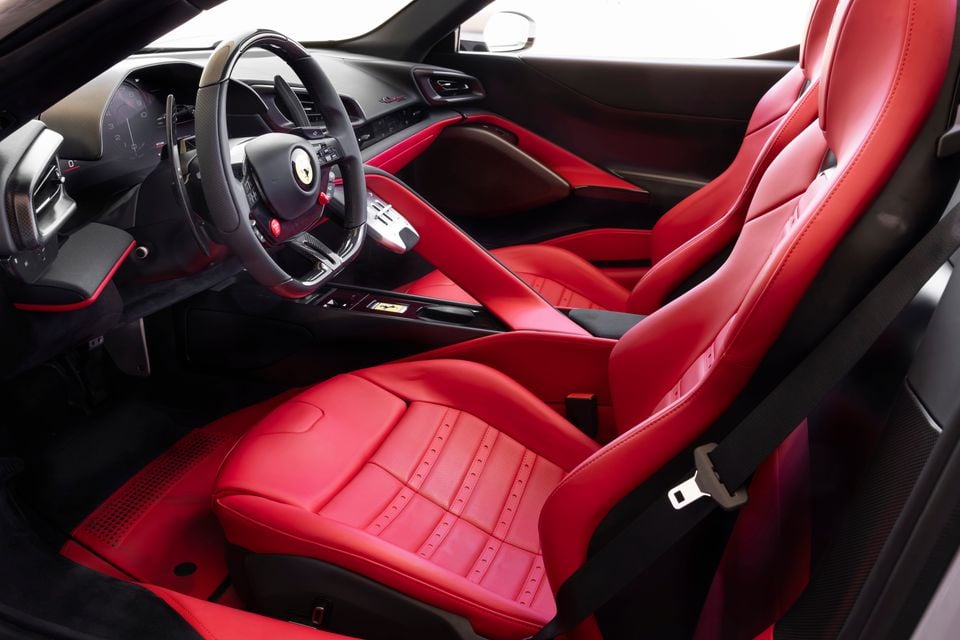 Ferrari interior with bold red leather bucket seats, carbon fibre trim, and a flat-bottomed steering wheel with prancing horse badge