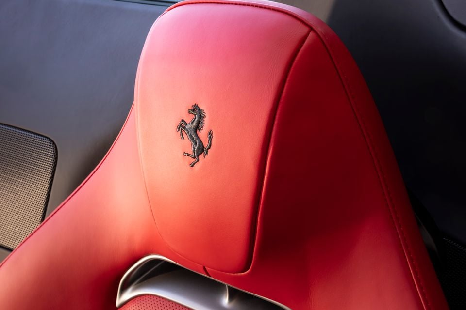 Close-up of a red leather Ferrari seat headrest with the embroidered Prancing Horse logo