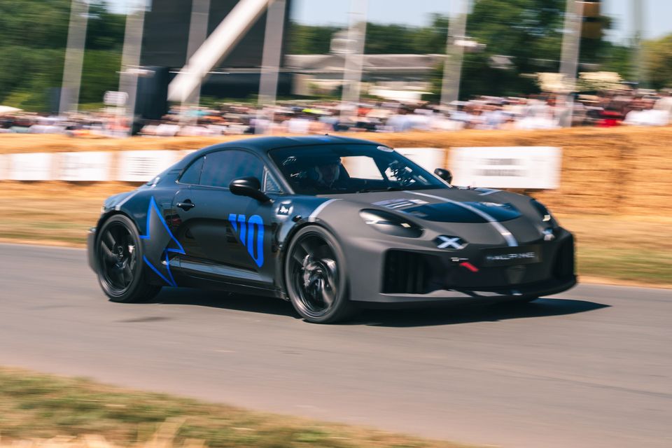 Um protótipo sucessor do Alpine A110 cinza escuro com pintura de estrela azul dirigindo rápido no Goodwood Festival of Speed ​​​​em 2026