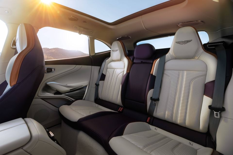 Rear seats inside an Aston Martin DBX GT showing white, purple and tan leather upholstery and a panoramic sunroof