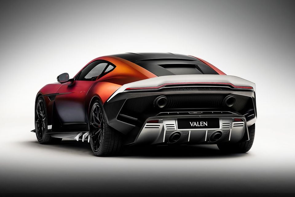 Aston Martin Valen supercar seen from the rear three-quarter angle, finished in a red-to-orange gradient with carbon fibre bodywork and aggressive diffuser