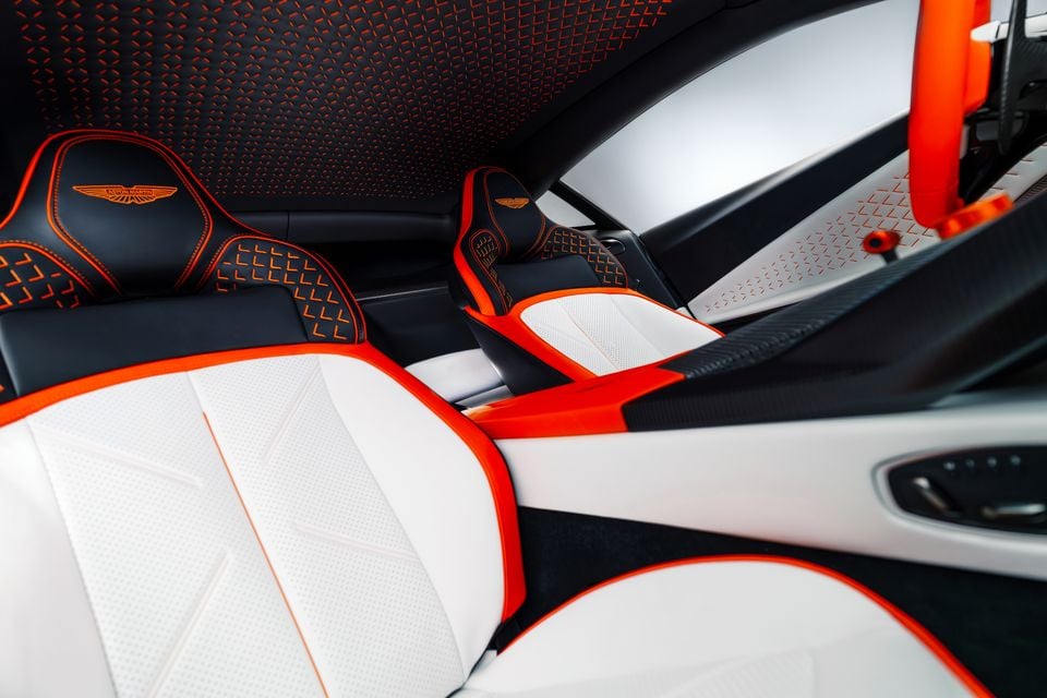 Aston Martin Valen interior showing white, black and orange sport seats with Aston Martin wing logo embroidery, orange roll cage and patterned headliner