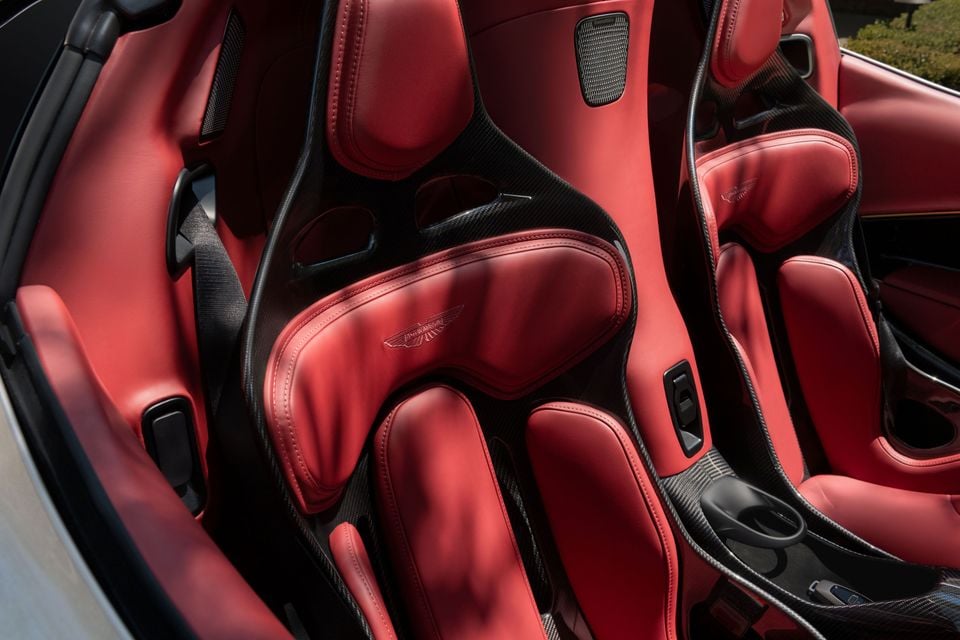 Red leather carbon-fibre bucket seats with embossed Aston Martin wings logos inside the open cabin of an Aston Martin Valhalla Spider