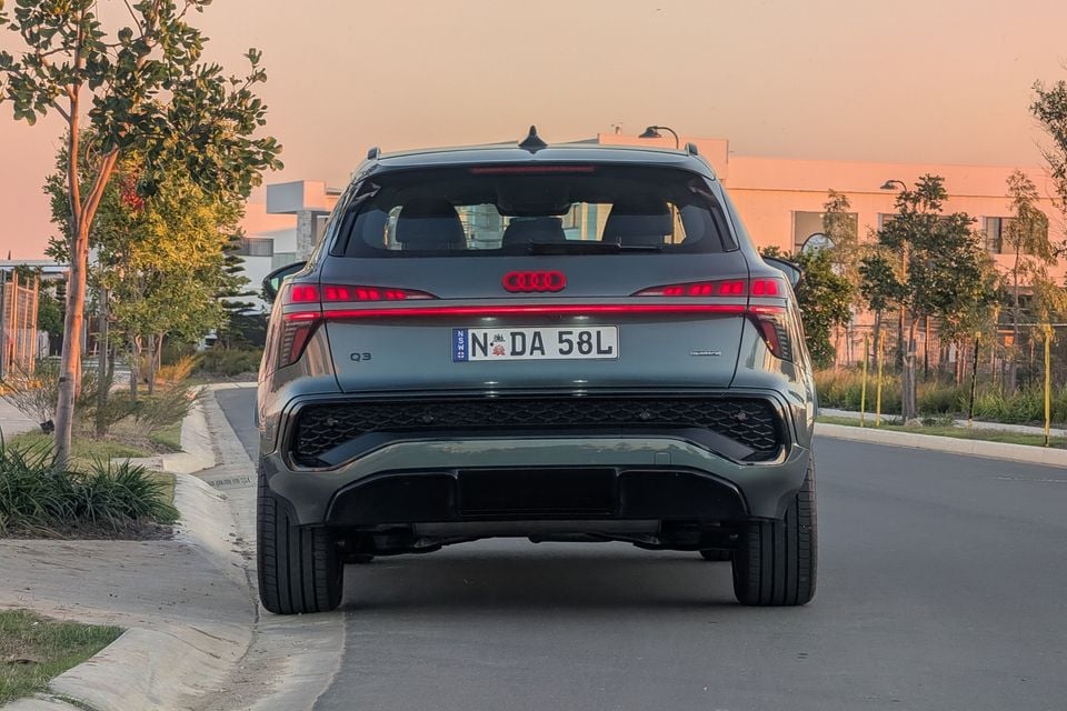 Rear view of a grey Audi Q3 SUV parked on a suburban street at sunset, with NSW number plates visible