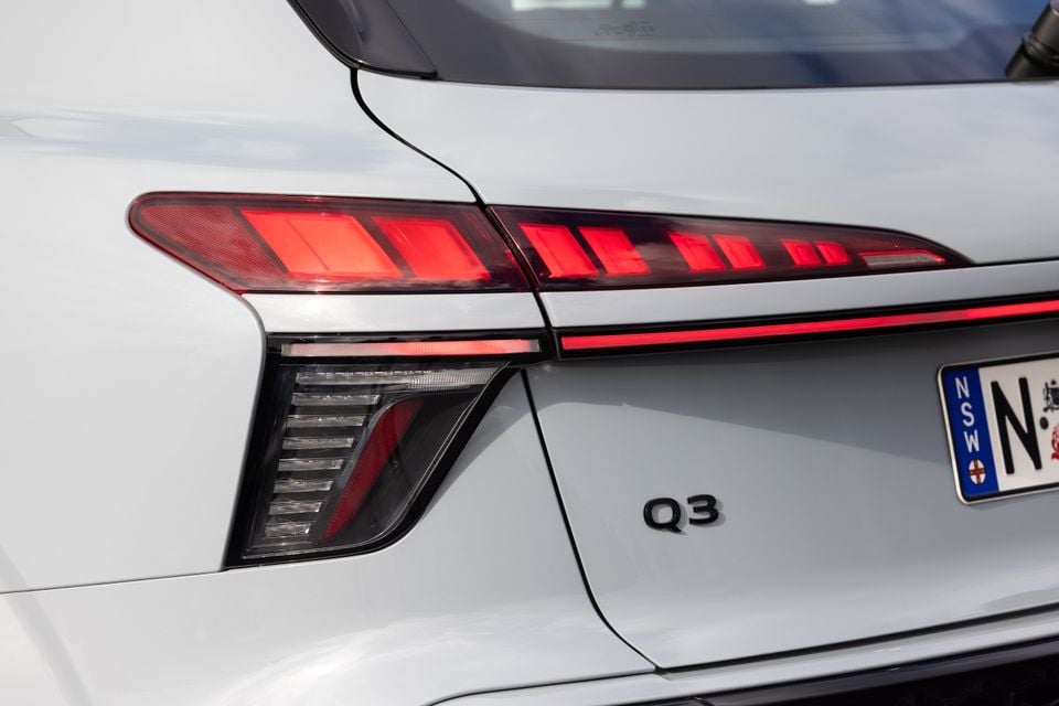 Close-up of the rear tail light and Q3 badge on a white Audi Q3 SUV, with a NSW number plate visible