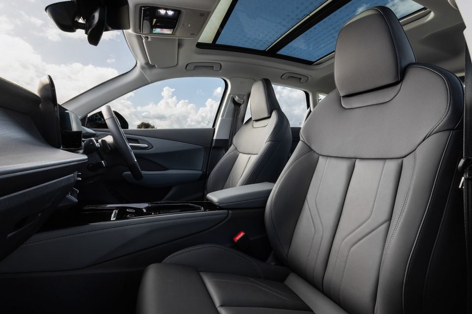 Interior view of a car showing dark leather front seats, centre console, steering wheel and panoramic sunroof