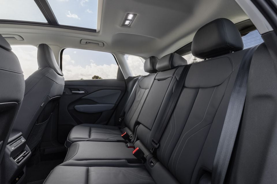 The rear interior of an Audi Q3 SUV showing dark leather rear seats with white contrast stitching, seatbelts, sunroof, and reading lights overhead.