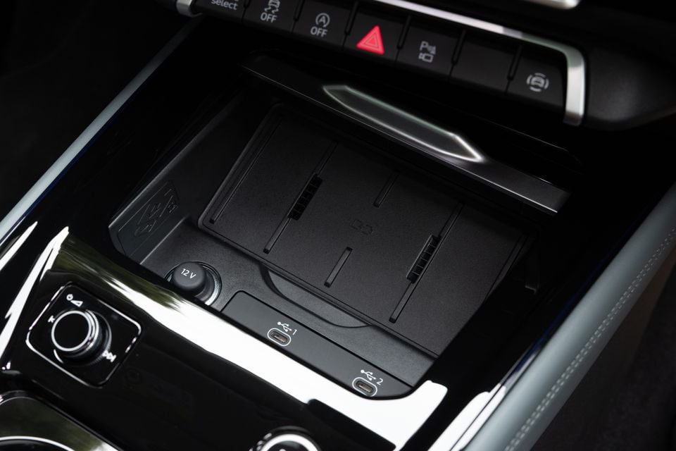 Close-up of the Audi Q3 centre console showing a wireless charging pad, dual USB-C ports, 12V socket, and overhead control buttons