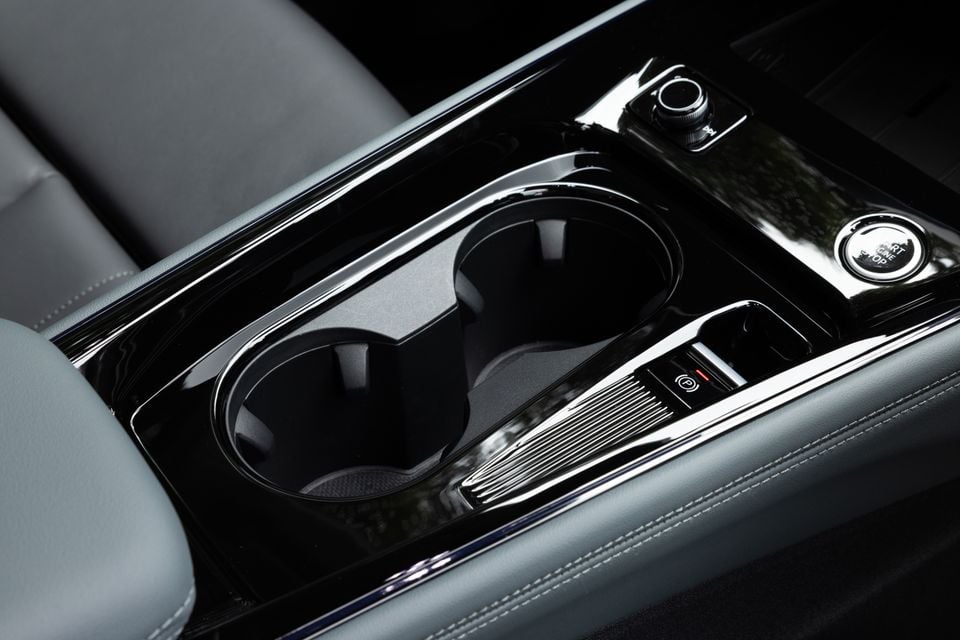 Close-up of the Audi Q3 centre console showing dual cup holders, electronic parking brake, and start/stop button with grey leather trim
