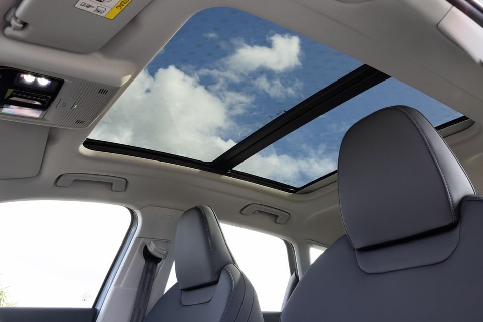 Interior view of an Audi Q3 SUV showing the panoramic sunroof, grey leather front seats, and overhead console with lights
