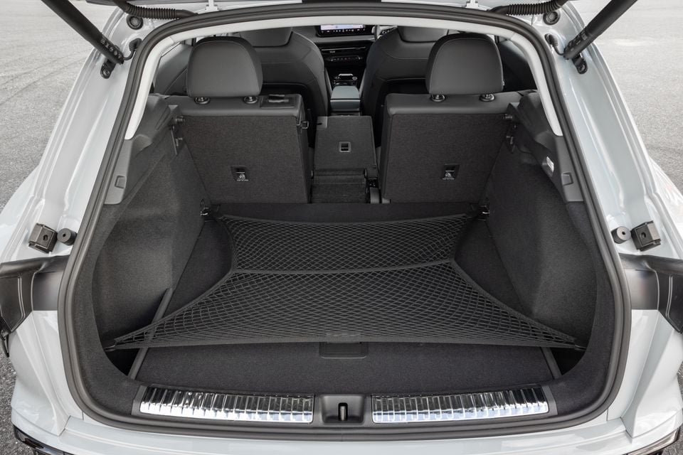 Boot interior of an Audi Q3 SUV showing a spacious cargo area with a cargo net, carpeted walls, and rear seats visible in the background