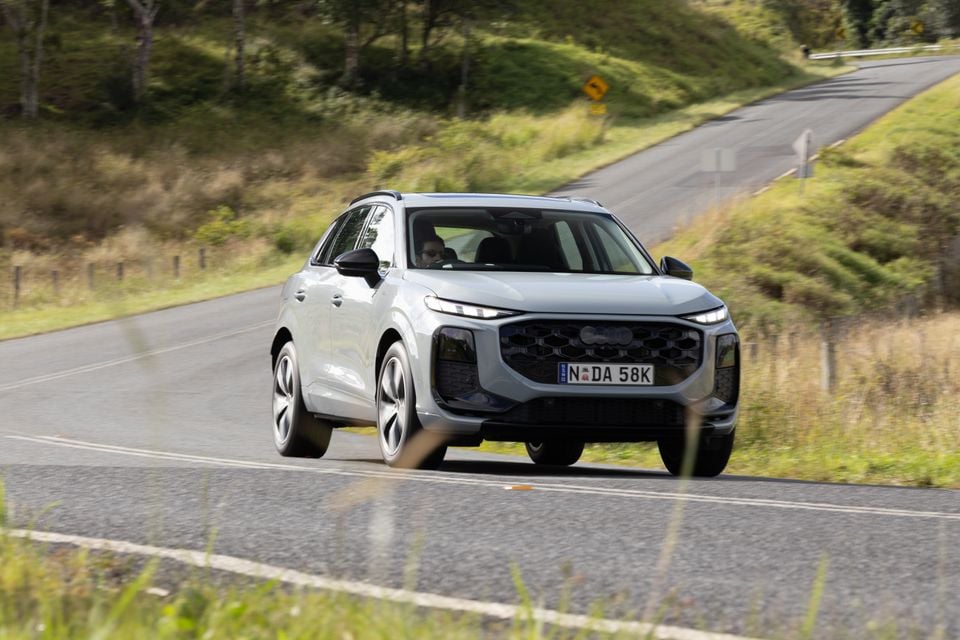 A silver Audi Q3 SUV driving on a country road, seen from the front