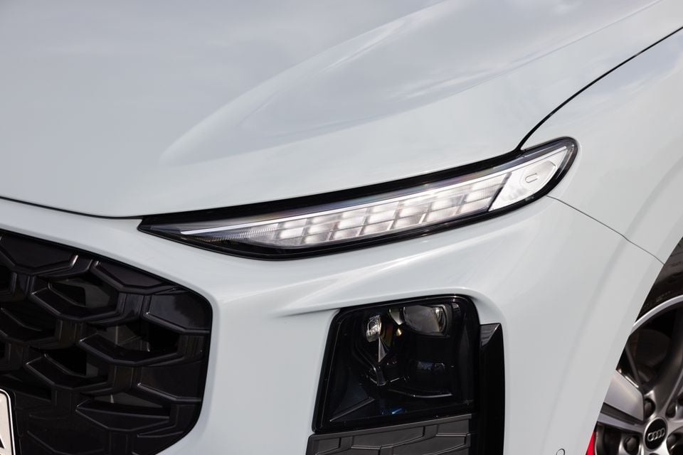 Close-up of the LED headlight and front grille of a white Audi Q3 SUV