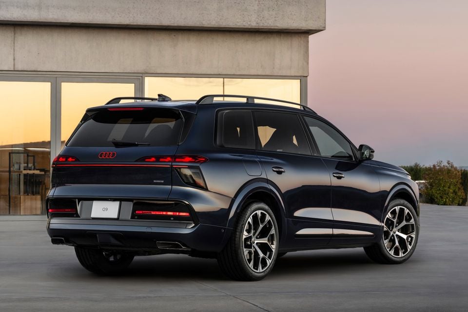 Dark blue Audi Q9 SUV seen from the rear three-quarter angle, parked outdoors at dusk