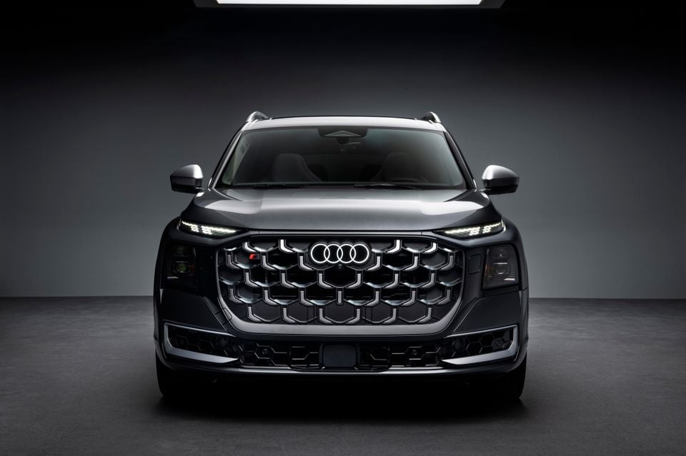 A dark grey 2026 Audi SQ9 SUV seen from the front in a studio setting, showcasing its large hexagonal grille and LED headlights