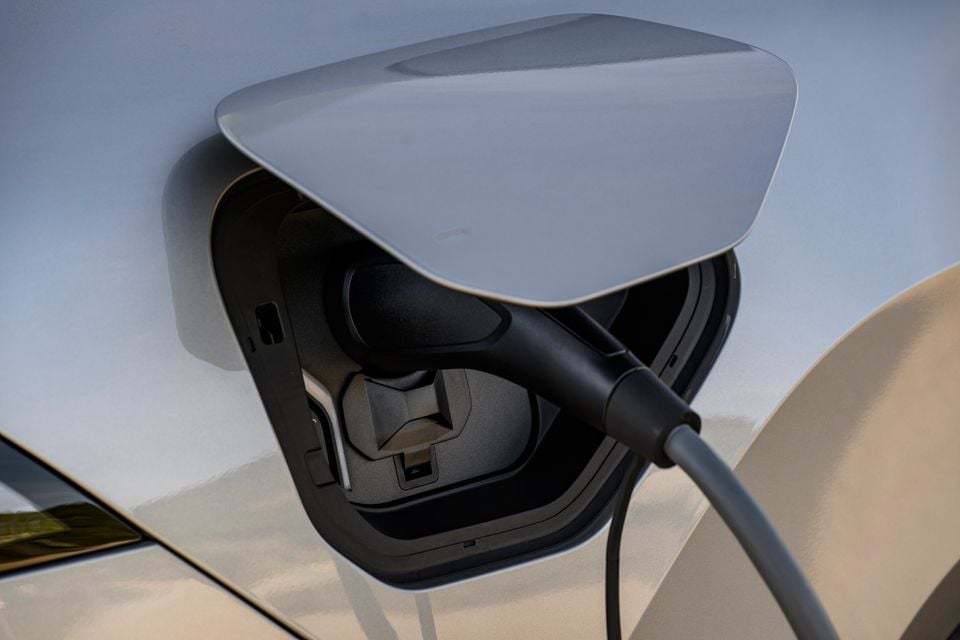 Close-up of an electric vehicle charging port with a charging cable plugged in on a BMW iX3