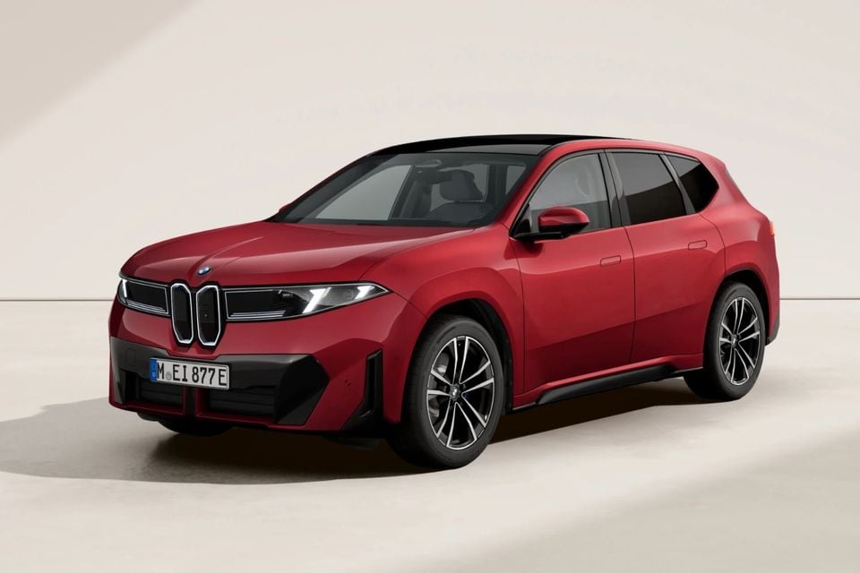 A red BMW iX3 SUV seen from the front-side angle against a neutral studio background