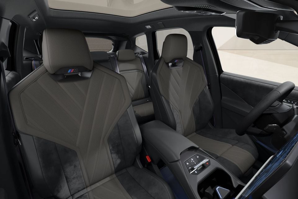 BMW iX3 interior showing M Sport front seats in dark brown and grey upholstery, with the centre console and steering wheel visible
